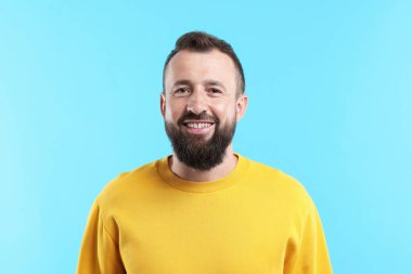 Yakışıklı adam açık mavi arka planda gülüyor.