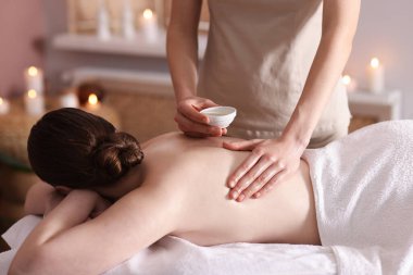 Spa salonunda kadın sırt masajı yaptırıyor.