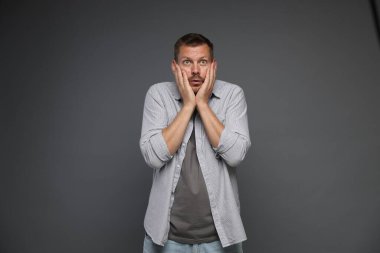 Gri arka planda panik atak geçiren bir adam.