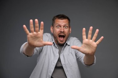 Gri arka planda panik atak geçiren bir adam.