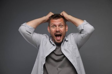 Gri arka planda panik atak geçiren bir adam.