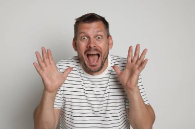 Açık gri arka planda panik atak geçiren bir adam.