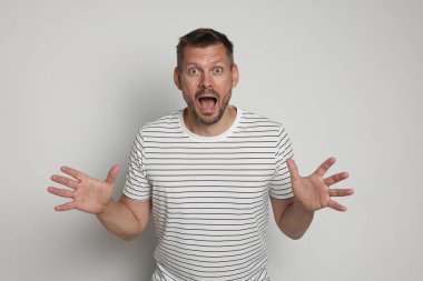 Açık gri arka planda panik atak geçiren bir adam.