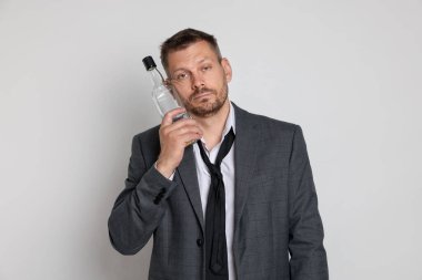 Beyaz arka planda akşamdan kalma viski şişesi olan bir adam.