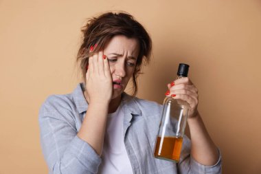 Bir şişe alkollü kadın bej arka planda akşamdan kalma.