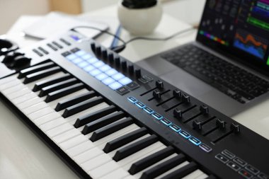 MIDI klavye ve dizüstü bilgisayar beyaz ahşap masa, yakın plan