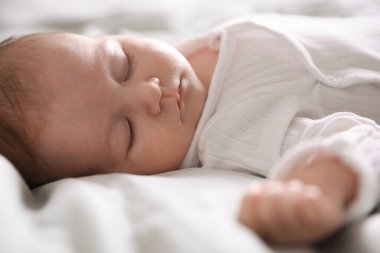 Sevimli yeni doğmuş bebek yatakta uyuyor, yakın plan.