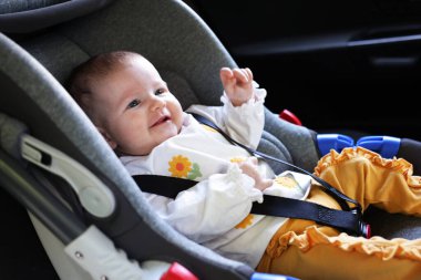Bebek koltuğuna bağlanmış şirin bir bebek.