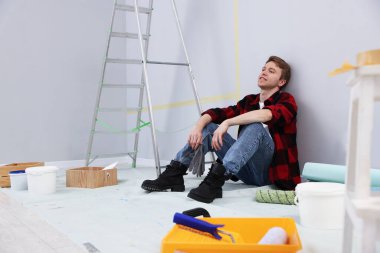 Odanın yenilenmesi sırasında mola veren bir adam.