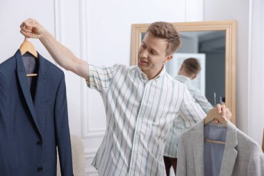 Hazırlanıyor. Genç adam evde kıyafet seçiyor.