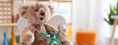 Çocuk doktoru konsepti. Oyuncak ayı ve steteskop klinikte, yakın plan. Metin için boşluk