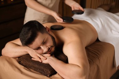 Adam spa salonunda taşlarla masaj yaptırıyor.