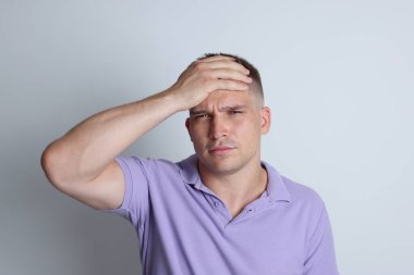 Açık gri arka planda akşamdan kalma bir adam.