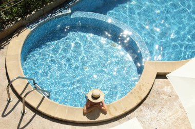 Açık yüzme havuzunda hasır şapkalı güzel bir kız.