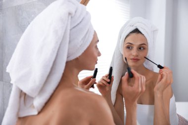 Hazırlanıyor. Evde aynanın yanında rimel süren genç bir kadın.