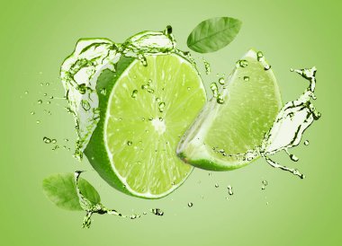 Taze kireç ve içecek yeşil arka planda havaya sıçrıyor