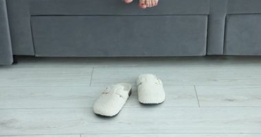 Evdeki kanepede beyaz terlik giyen kadın, yakın plan.