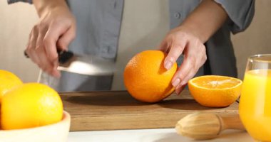 Meyve suyu. Beyaz masada turuncu kesen kadın, yakın plan.