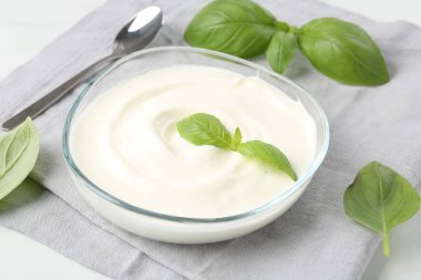 Lezzetli yoğurt ve fesleğen beyaz masada, yakın plan.