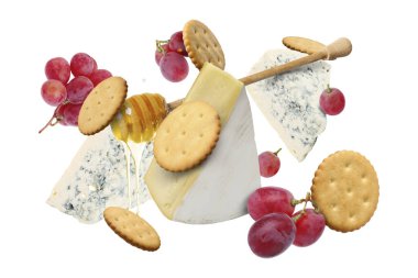 Peynir ürünleri beyaz arka planda havada. Farklı peynir, üzüm, kraker ve bal çeşitleri.