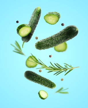 Taze salatalıklar, biberiye ve biber taneleri açık mavi arka plana düşüyor.