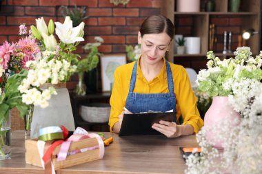 Dükkandaki ahşap masada çalışan profesyonel bir çiçekçi.