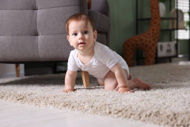 Evdeki halının üzerinde emekleyen sevimli küçük bebek.