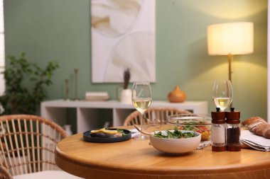 Lezzetli yemekler ve şık bir odada beyaz şarap olan yemek masası.