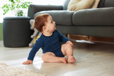 Evde yerde oturan şirin bir bebek.