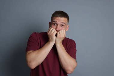 Gri arka planda panik atak geçiren bir adam.