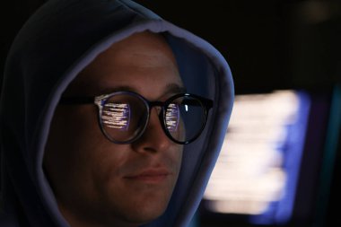 Arka planda yansıması olan gözlük takan genç adam, yakın plan.