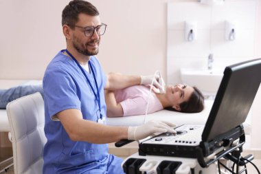 Klinikte kadının tiroid bezini ultrason taraması yapan sonograf.