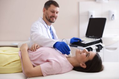 Klinikte kadının tiroid bezini ultrason taraması yapan sonograf.