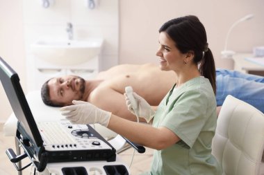 Ultrason çeviricili sonograf ve klinikte muayene için bekleyen adam, seçici odaklanma