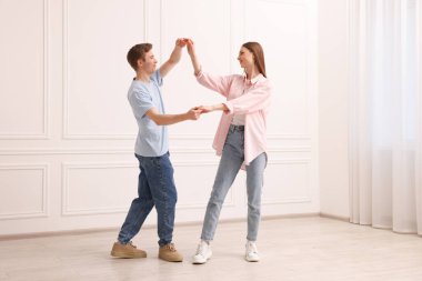 Mutlu çift evde beyaz duvarın yanında dans ediyor.