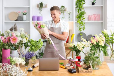 Profesyonel çiçekçi dükkandaki ahşap masada çiçek buketi yapıyor.