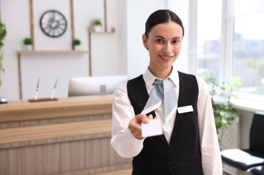 Üniformalı gülen resepsiyonist otelde anahtar kartı veriyor. Metin için boşluk