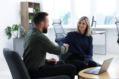 Gülümseyen iş ortakları ofiste el sıkışıyor.