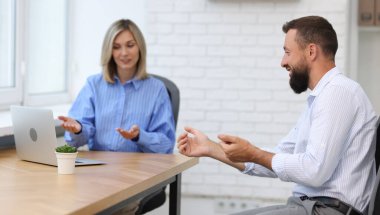 Ofiste dizüstü bilgisayarla çalışan gülümseyen iş ortakları