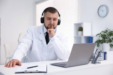 Kulaklıklı doktor içeride bilgisayarla online danışmanlık yapıyor.