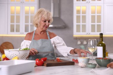 Mutfaktaki masada yemek pişiren son sınıf kadını.