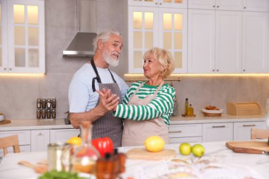 Mutfakta birlikte yemek pişirirken dans eden yaşlı çift.