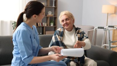 İçeride yaşlı bir kadını muayene eden bir hemşire. Ev sağlık hizmetleri