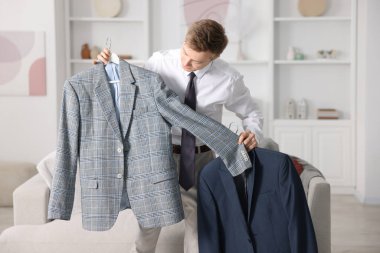 Hazırlanıyor. Genç adam evde kıyafet seçiyor.