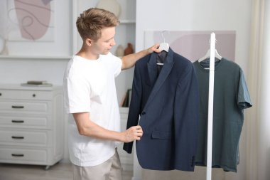 Hazırlanıyor. Genç adam evde kıyafet seçiyor.