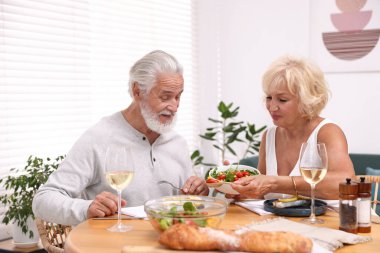 Evde yemek yiyen yaşlı bir çift.