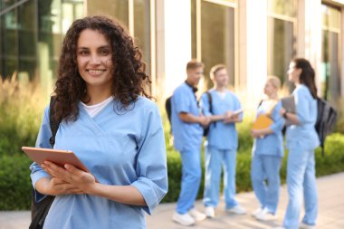 Açık hava binasının yanında sırt çantası ve tabletli mutlu tıp öğrencisi, seçici odaklı.