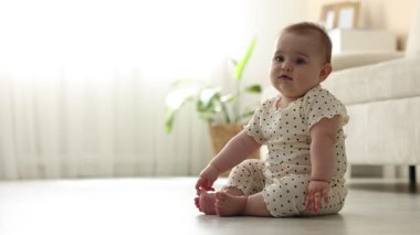 Evde yerde oturan şirin bir bebek.