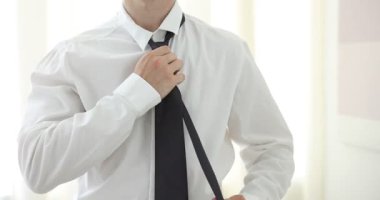 Hazırlanıyor. Genç adam evde şık kravat bağlıyor, yakın plan. Kamera yukarı hareket ediyor