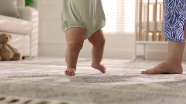 Anne bebeğine evde nasıl yürüyeceğini öğretiyor.